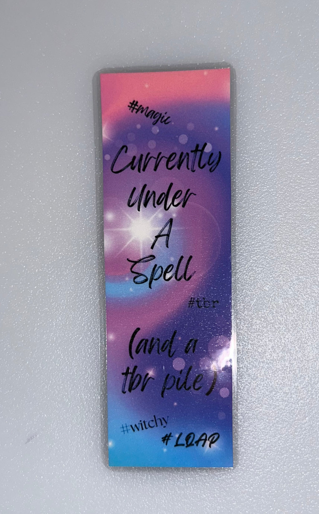 Pastel gradient bookmark with sparkles — “Currently Under A Spell (and a TBR pile)”